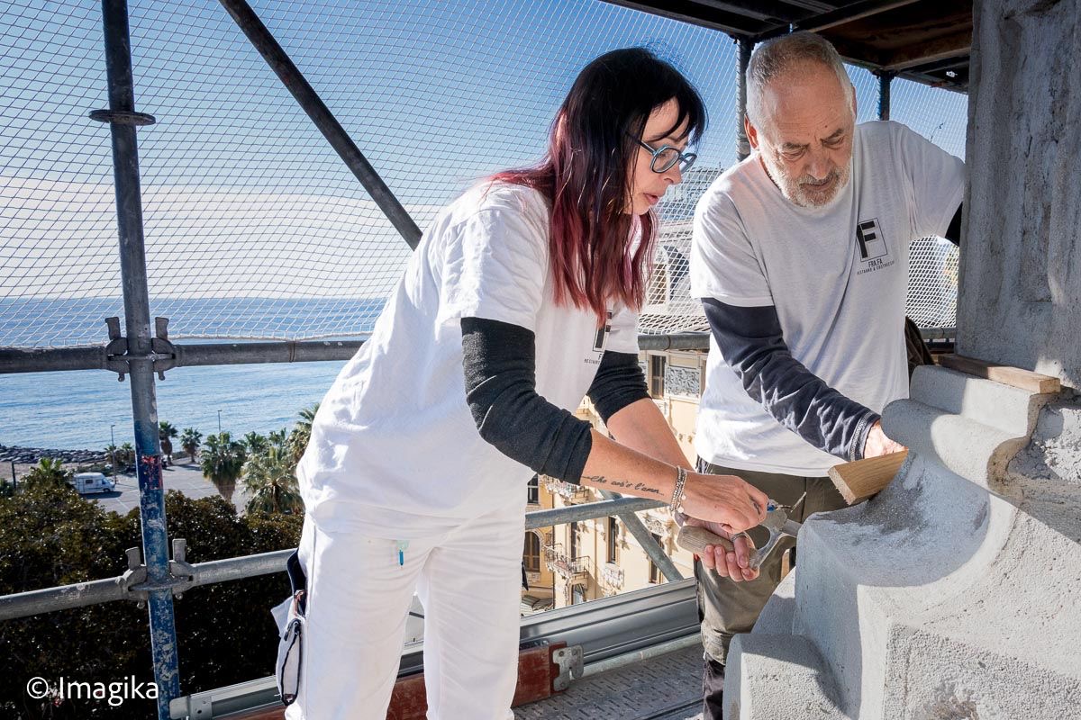 Due restauratori al lavoro su un ponteggio con vista sul mare